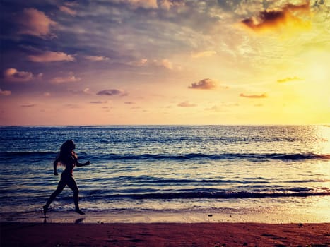 Health sporty fitness fit life concept background. Vintage retro effect filtered hipster style image of beautiful athletic woman running along sea on the beach in the morning