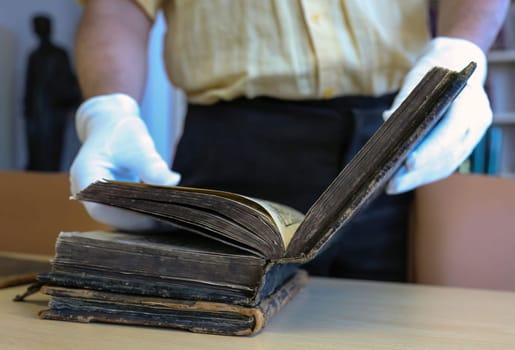 An old book on a wooden table, close-up. Christian religious book in the hands of a librarian.