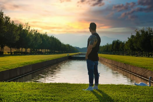 A man standing in front of a body of water. Photo of a man standing by the shore of a serene body of water