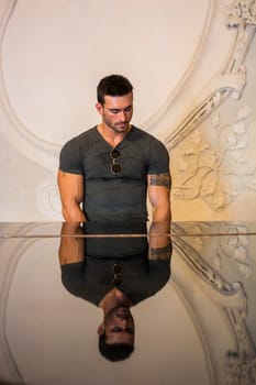 A man standing in front of a glass table. Photo of a man standing in front of a glass table