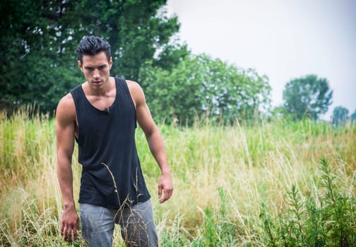 A man standing in a field of tall grass, during an adventurous trip, maybe he's lost