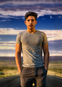 A young attractive man standing in the middle of a road. Photo of a man standing in the middle of a road