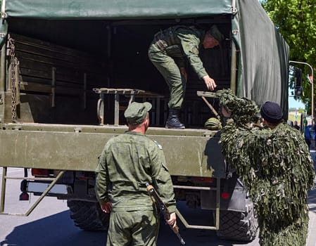 Soldiers unload firearms from a military truck. A soldier in the back of a truck.