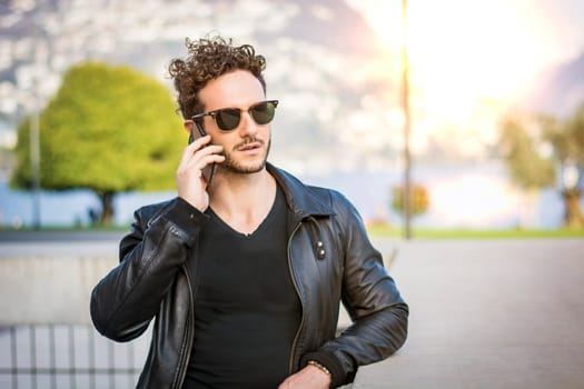 A man in a leather jacket talking on a cell phone. Photo of a man in a leather jacket talking on a cell phone