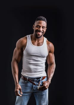 A man in jeans and a tank top posing for a picture. Photo of a man posing in casual attire for a stylish and relaxed photoshoot smiling to the camera
