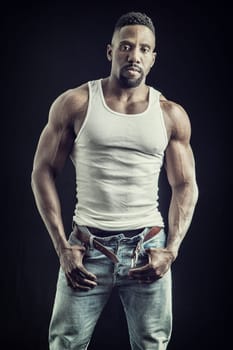 A man in jeans and a tank top posing for a picture