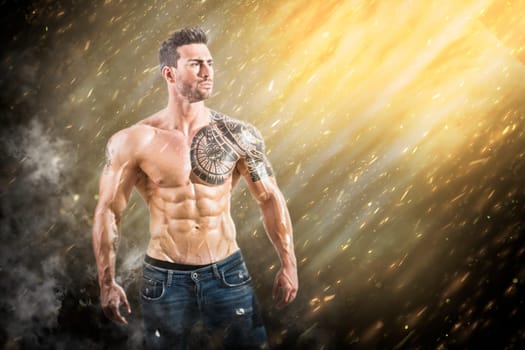 A man with a tattoo on his arm standing in the rain. Photo of a tattooed man standing in a rain of sparks and lights, showcasing his muscular physique