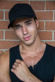 A man in a black shirt and a black hat. Photo of a stylish and handsome young man wearing a black shirt and hat smiling to the camera