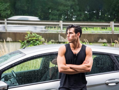 A man standing in front of a car with his arms crossed