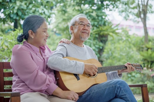 Asian senior couple elderly man playing guitar while his wife singing together outdoors at house, Activity family health care, Enjoying lifestyle during retirement life having fun of senior older