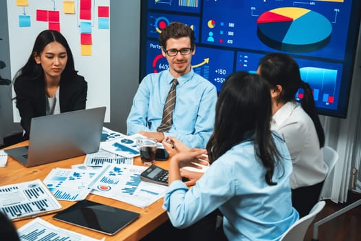 Diverse group of business analyst team analyzing financial data report. Finance data analysis chart and graph dashboard show on TV screen in meeting room for strategic marketing planning. Habiliment