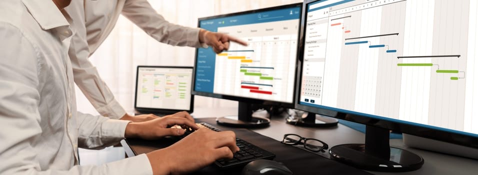 Project management team coordinating and update project planned schedule on computer using Gantt chart software in office. Business people planning time and deadline for company task. Trailblazing