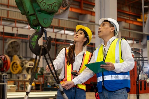 Factory foreman worker and engineer conduct inspection of industrial steel machine and metal material quality product. Manufacturing facility with machinery safety and quality control. Exemplifying