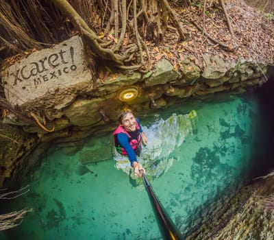 09.12.24, Playa Del Carmen, Mexico: Man tourist standing in the water of a cenote at Xcaret park wearing a marked life jacket. Mexican tourism in natural parks. Adventure, relaxation, and eco-tourism concept in Quintana Roo.