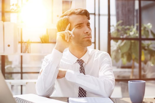 Image of successful 30s businessman thinking and holding index finger near forehead in office