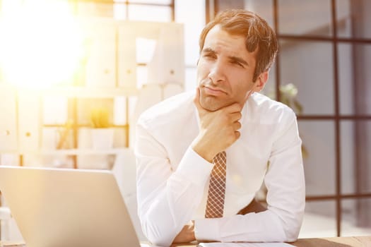 Image of successful 30s businessman thinking and holding index finger near forehead in office