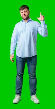 A man with a friendly smile gestures upwards while wearing a navy shirt against a bright green background in studio