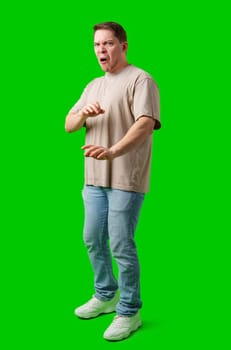 Young man making a disgusted expression while standing against a bright green background in studio