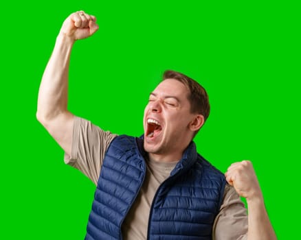 Man celebrating with raised fists in front of a bright green background in studio