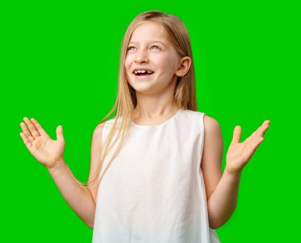 A young girl with long hair in a white dress poses with open arms against a vibrant green background