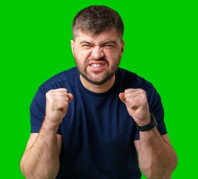 A strong man with fists raised, smiling confidently, on a bright green background in studio