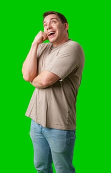 Smiling man in a beige shirt poses against a bright green background in studio