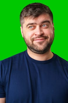 A young man smiles playfully against a bright green backdrop, showcasing a cheerful expression in studio