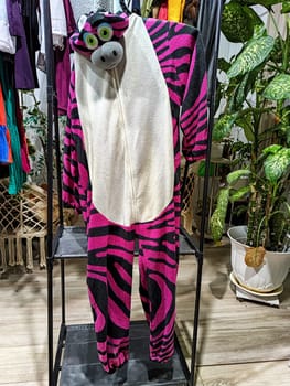 Discover a vibrant zebra onesie among a variety of second-hand clothing at a garage sale promoting eco-friendly choices.