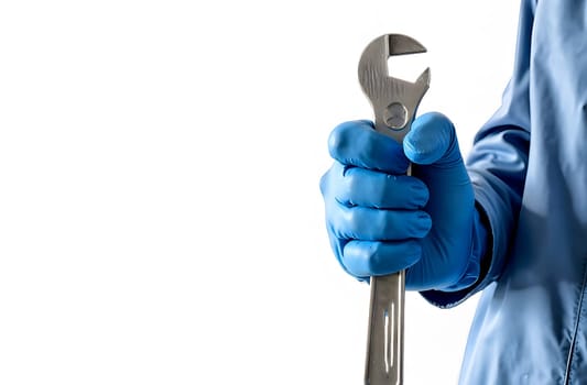 A worker in blue gloves grips an adjustable wrench, preparing for mechanical repair or maintenance in a sterile setting.
