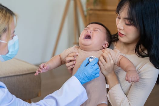 A pediatrician assesses a distressed infant, with the concerned parent close by, in a calm and inviting healthcare environment.
