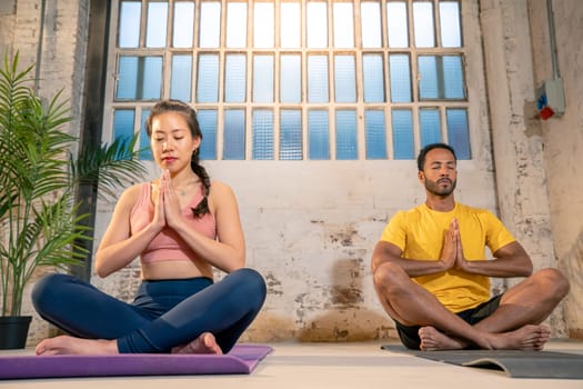 In a serene and welllit room radiating warmth, two individuals are deeply engaged in practicing yoga and meditation