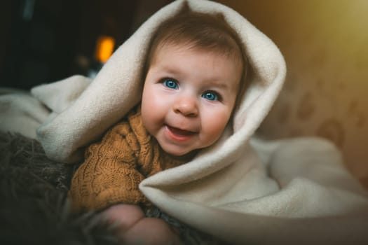 Smiling baby girl crawling on bed under the blanket. Adorable kid portrait. 5 month old child. Childhood concept. High quality photo