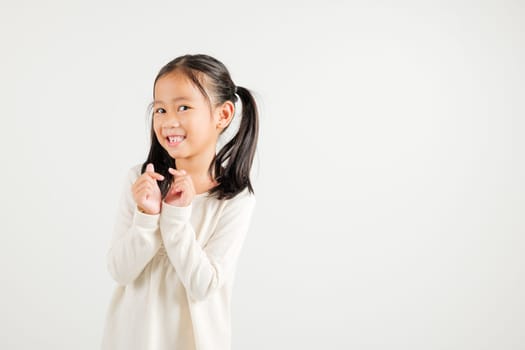 Portrait of happy Asian young kid girl, confidently smiling showing mini heart sign with finger studio shot isolated on white background. Kindergarten child expressing love and joy for Valentine's Day