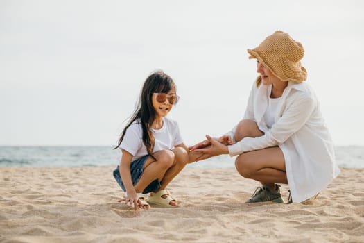 Loving family enjoys beach fun. Mother and daughter sitting on the sand playing and bonding. Caribbean vacation joy freedom and happiness. Sunset portrait of care and togetherness
