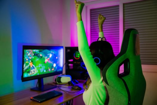 Winning. Young woman in gaming headphones playing video game online at home neon room feel excited, Happy Gamer young plays online video games computer she raises hands to wins tournament, E-Sport