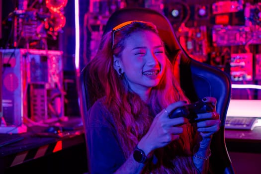 Gamer using joystick controller for virtual tournament plays online video game with computer neon lights dark room, woman wear gaming headphones playing live stream esports games console at home