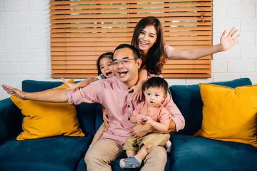 In their modern home an interracial family plays plane games creating a joyful atmosphere with their daughter. Their family portrait reflects happiness and togetherness.