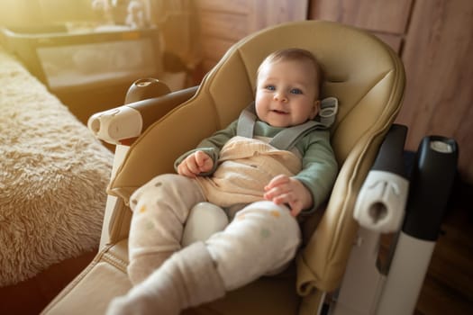 Cute 5-month old baby sitting and smiling in chair. Adorable kid portrait. Childhood and babyhood concept. High quality photo