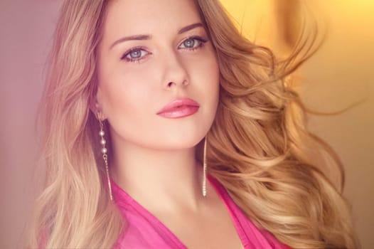 Woman with blue eyes and long, voluminous blonde hair styled in soft curls, wearing pink dress and elegant earrings, dreamy and feminine look idea