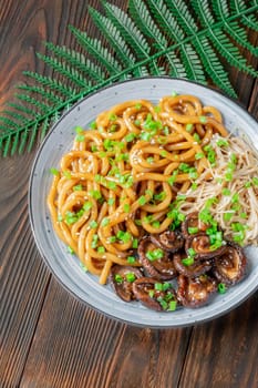 A portion of udon noodles with soy unagi mirin ginger sauce, shiitake and enoki mushrooms, and green onion