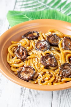 A portion of udon noodles with soy unagi mirin ginger sauce, shiitake and enoki mushrooms, and green onion