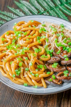 A portion of udon noodles with soy unagi mirin ginger sauce, shiitake and enoki mushrooms, and green onion