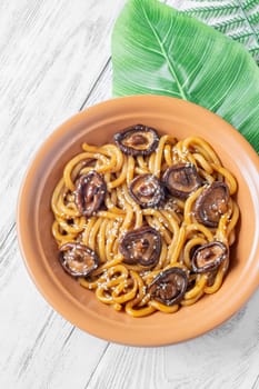 A portion of udon noodles with soy unagi mirin ginger sauce, shiitake and enoki mushrooms, and green onion
