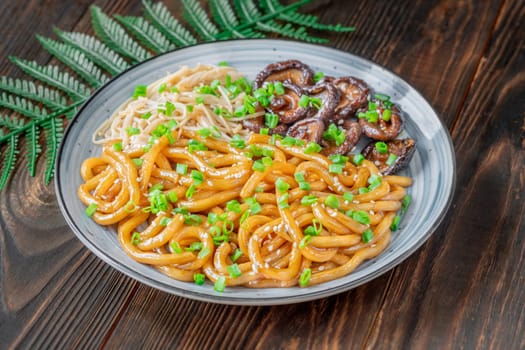 A portion of udon noodles with soy unagi mirin ginger sauce, shiitake and enoki mushrooms, and green onion