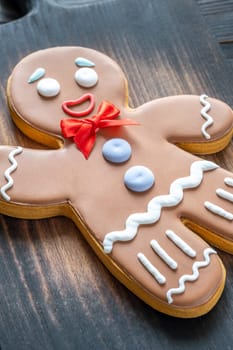 A large gingerbread man cookie with a red bow on a wooden cutting board