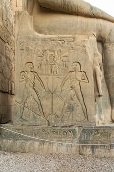 Engravings on base of massive stone statue of Ramesses II stands in Luxor temple