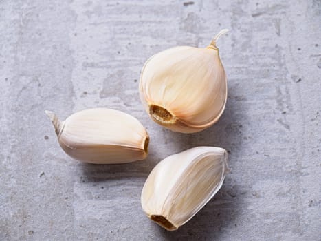 A flat lay photo of three garlic cloves on a table.