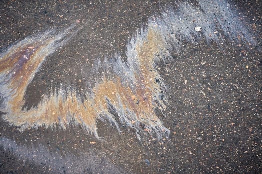 Gasoline or oil is creating colorful patterns on asphalt road.