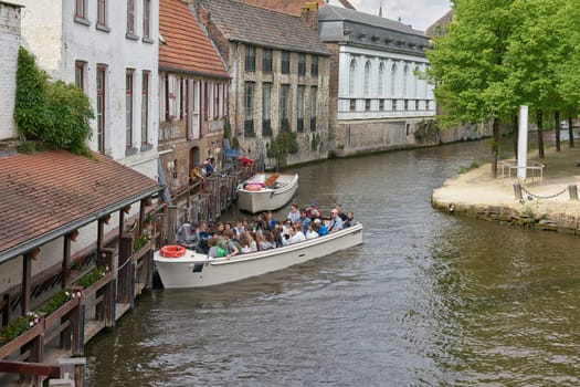 Bruges, Belgium – May 13, 2024: Canal in the old town of Bruges with excursion boats for tourists