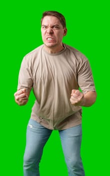 Man expressing intense frustration while standing against a bright green background in studio